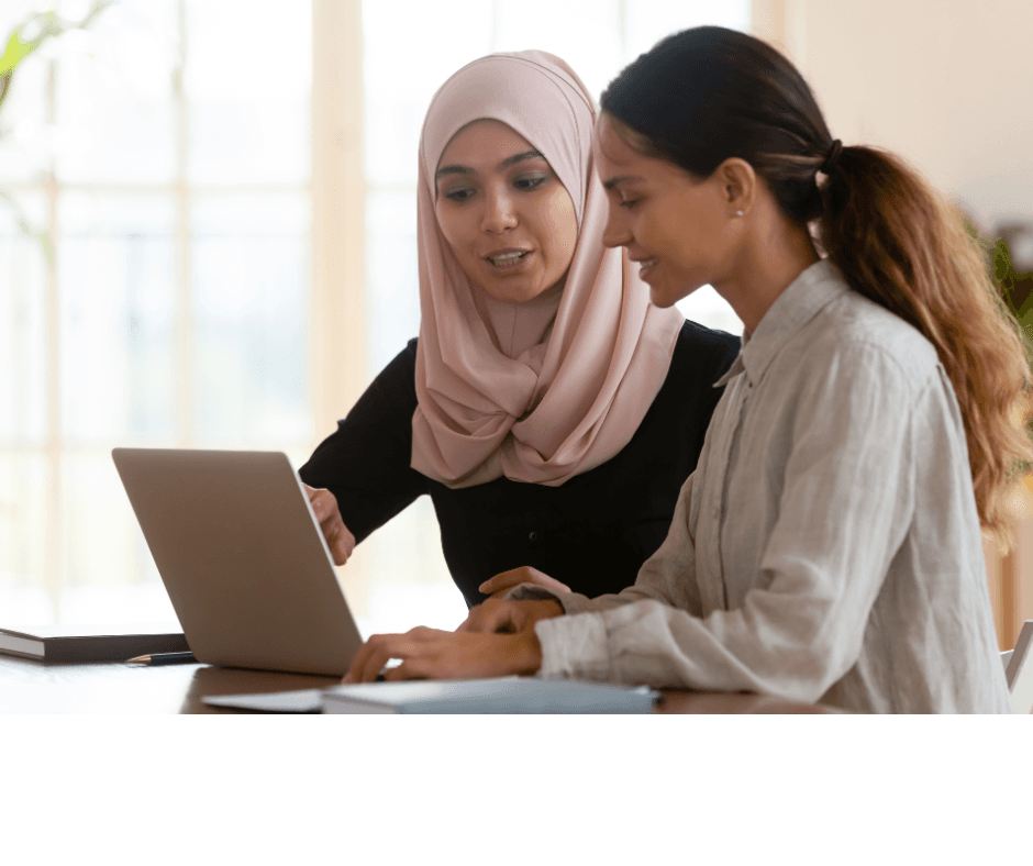 Two people looking at a laptop in conversation 