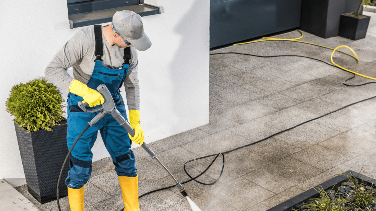 man cleaning driveway with water blaster