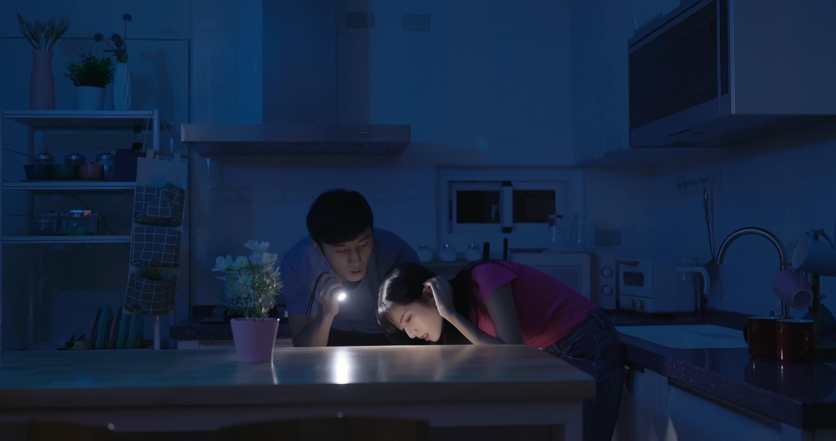 Couple searching with a torch while the power is out.